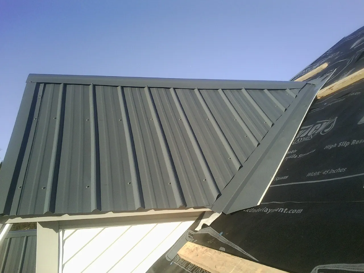 Gray metal roof panels going on over a garage gable in Viewtown