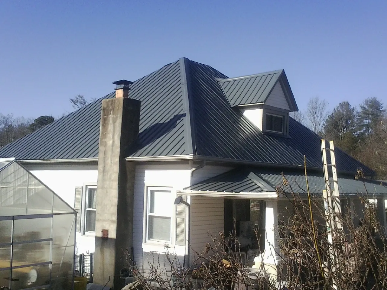 Dark blue standing seam metal roof on a white farmhouse with dormer — Slate & Tile Roof Repair by Roofing Brothers in Viewtown