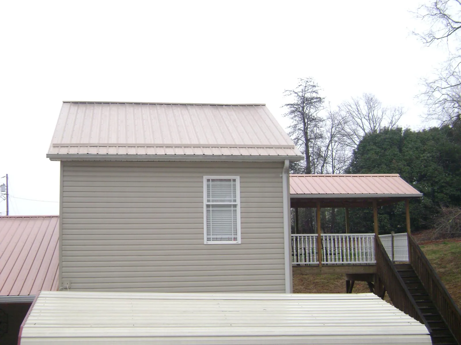 Tan metal roofs on a two story addition and attached porch, from a Roof Replacement job in Viewtown